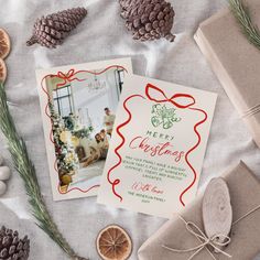 two christmas cards with pine cones and other holiday decorations on top of a tablecloth