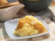 mashed potatoes covered in caramel sauce on a plate next to a gravy