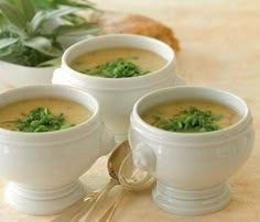 three white bowls filled with soup on top of a table