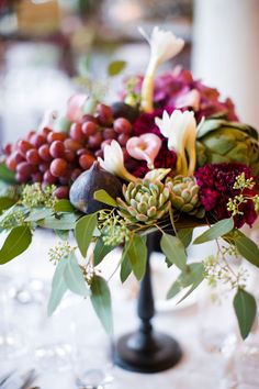 a vase filled with flowers and greenery on top of a table