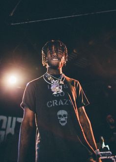 a man standing on top of a stage wearing a black t - shirt and necklace