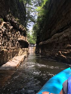 a man in a kayak paddles through a narrow river surrounded by rocky cliffs