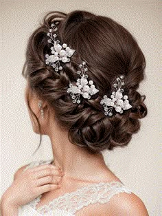 a woman wearing a bridal hair comb with flowers in her hair and pearls on the side