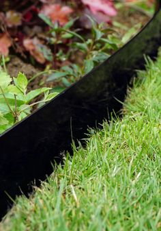 a black planter sitting in the middle of some grass