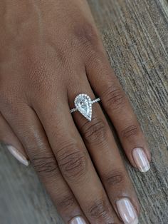 a woman's hand with a diamond ring on top of her left hand,