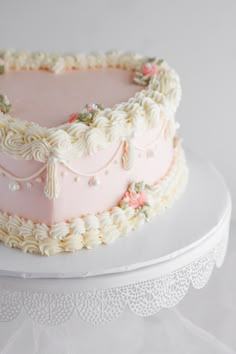 a pink cake with white frosting and flowers on the top is sitting on a platter