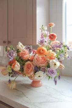 a vase filled with lots of different colored flowers on top of a white countertop