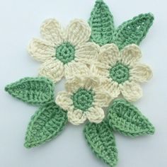 crocheted flowers with green leaves on white background