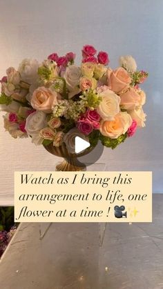 a vase filled with pink and white flowers on top of a metal table next to a sign that says watch as i bring this arrangement to life, one flower at a time