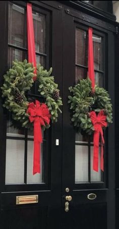 two christmas wreaths are hanging on the front door