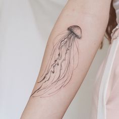 a woman's arm with a jellyfish tattoo on it