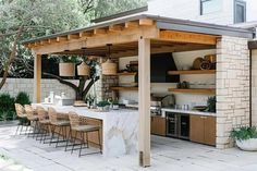 an outdoor kitchen and dining area is shown in this backyard setting with chairs, counter tops, and bar stools