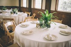 the table is set with white plates and place settings