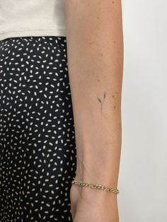 a woman's arm with a tattoo on it and a gold chain around the wrist