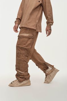 The Distressed Multi-Pocket Layered Cargo Pants in Earth perfectly merge street style with practicality. These cargo pants feature multiple flap pockets on both sides, providing ample storage and a rugged look. The elasticized cuffs create a natural stacking effect when worn, while zippers on the cuffs allow for an adjustable fit around the calves, enhancing mobility. The washed, distressed finish adds a unique edge to the design. Made from premium 100% cotton fabric, these slightly oversized pa Urban Baggy Parachute Pants With Multiple Pockets, Urban Relaxed Fit Parachute Pants With Multiple Pockets, Urban Cargo Pants With Multiple Pockets, Urban Style Baggy Cargo Pants, Streetwear Full-length Parachute Pants With Patch Pockets, Streetwear Full Length Parachute Pants With Patch Pockets, Urban Parachute Pants With Multiple Pockets, Urban Baggy Cargo Jeans With Multiple Pockets, Brown Straight Leg Cargo Pants With Multiple Pockets