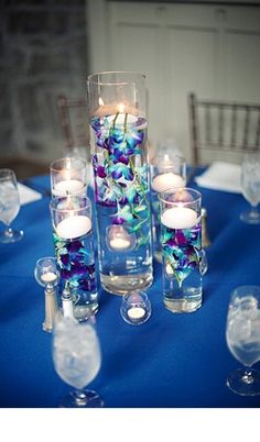 a table topped with lots of glass vases filled with candles