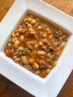 a white square bowl filled with beans and meat