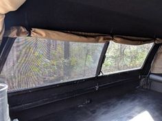 the back end of an old pickup truck with its cargo compartment open and trees in the background