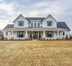 a large white house sitting on top of a dry grass field