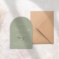 a wedding card and envelope on top of a white table with an envelope in the middle