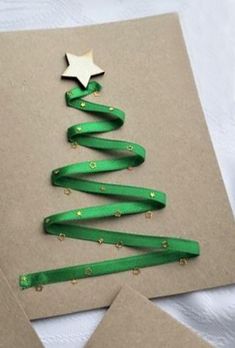 a christmas tree made out of green ribbon on top of some brown paper with gold stars