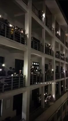 people are standing on the balconies of a building at night with their lights on