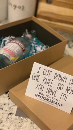 an open box with a note attached to it sitting on a counter next to two mugs