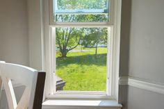 an empty chair sitting in front of a window with the view of a yard outside