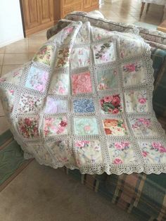 a crocheted blanket with flowers on it sitting on top of a couch in a living room