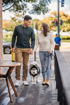 a man and woman walking their dog down the street