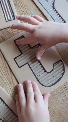 a child's hand touching the letter g on cardboard