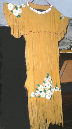 Handgemachtes Cherokee Rose Leder Kleid ist aus weichen Hirschhäuten mit vielen Fransen.  Jede einzelne Rosenblüte und blatt wird einzeln von Hand perlengestickt und anschließend unabhängig voneinander mit Künstlichem Sinew für einen sicheren Sitz aufgenäht. Hergestellt aus drei goldenen Hirschhäuten, jeder Fransen wird individuell von Hand geschnitten. Seitliche Schnürung geben etwas Flexibilität in der Breite; Halsausschnitt ist weißes Hirschfell, beschnitten mit roten Glas-Saatperlen.  Blumen Cherokee Rose, Jingle Dress, Cherokee Dress, Golden Deer, Native Dress, Deer Hide, White Deer, Native American Beading, Glass Seed Beads