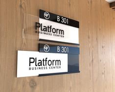 two signs are hanging on the wall in front of a wood paneled door that says platform business center