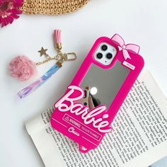 a pink phone case sitting on top of an open book next to a keychain