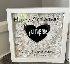 a white frame with a black heart in the center and happy anniversary written on it