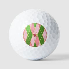 a white golf ball with pink and green argyle print