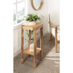 a small wooden table with a potted plant on it next to a mirror and chair