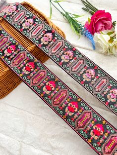 two black and pink embroidered ribbons next to flowers on a white cloth covered tablecloth