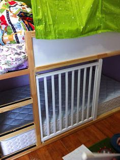 a child sitting on the floor in front of a bunk bed with a green cover over it