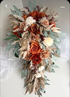 an arrangement of flowers and leaves on a white surface