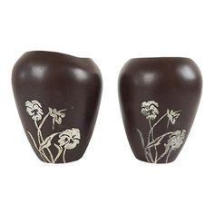 two brown vases with white flowers on them sitting next to each other in front of a white background