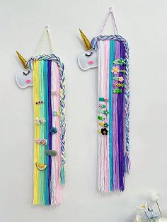 two wall hangings made out of rainbow colored yarn and unicorn horn hair clips, each with different designs on them