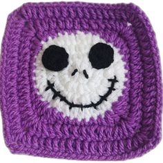 a crocheted square with a smiling skeleton on it's face in purple and white