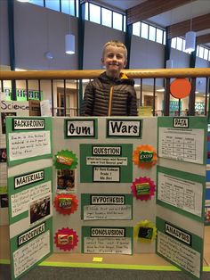 a young boy standing in front of a bulletin board with words and pictures on it