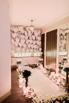 a long table with candles and flowers on it in front of a sign that says marry me