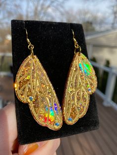 These gorgeous one of a kind  butterfly/fairy wing earrings are handmade with resin and are very lightweight. They are iridescent and holographic and will be sure to make a statement on your ears 💖 Handmade by Katie  KG Design & Decor Please follow my on social media  Instagram: @KG_DesignandDecor Facebook: KG Design and Decor Please be aware that this is handmade art and perfection has no place in art.  However, this was crafted with love and intention and I hope you are satisfied with your pu Gold Fantasy Earrings For Party, Gold Fairy Style Handmade Earrings, Gold Fairy Earrings For Gift, Gold Handmade Fairy Earrings, Handmade Gold Fairy Earrings, Iridescent Fantasy Jewelry For Parties, Iridescent Butterfly-shaped Handmade Jewelry, Iridescent Fairy Jewelry For Parties, Iridescent Fairy Style Jewelry For Party