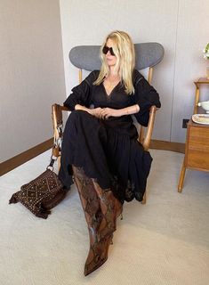 a woman sitting in a chair with her legs crossed and purse on the floor next to her