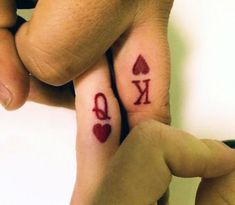 two people with matching tattoos on their fingers holding each other's hands and the word love is written in red ink