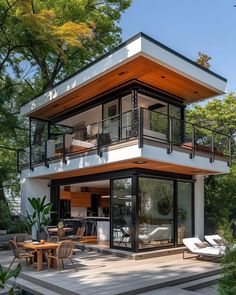 a modern house with an outdoor deck and dining area in the middle of the yard