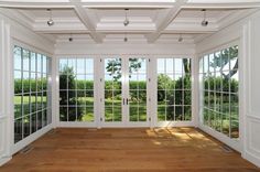 an empty room with large windows and wood flooring on either side of the doors